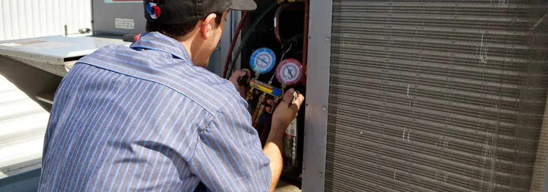 HVAC technician servicing a condenser unit in Barnstead