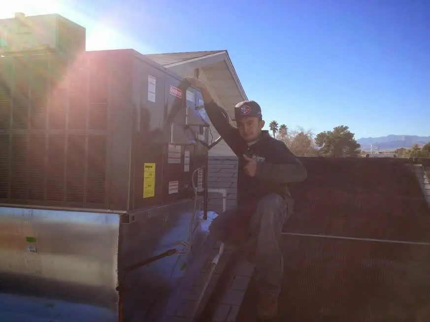 HVAC technician performing Air Duct Cleaning on a rooftop unit in Barnstead